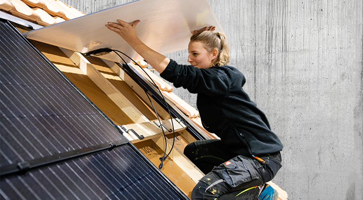 Solarinstallateurin arbeitet auf Steildach und installierte eine Solaranlage Gebäudehülle Schweiz
